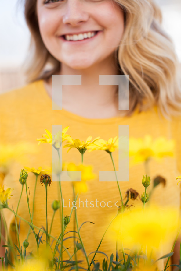 a woman standing behind yellow flowers 
