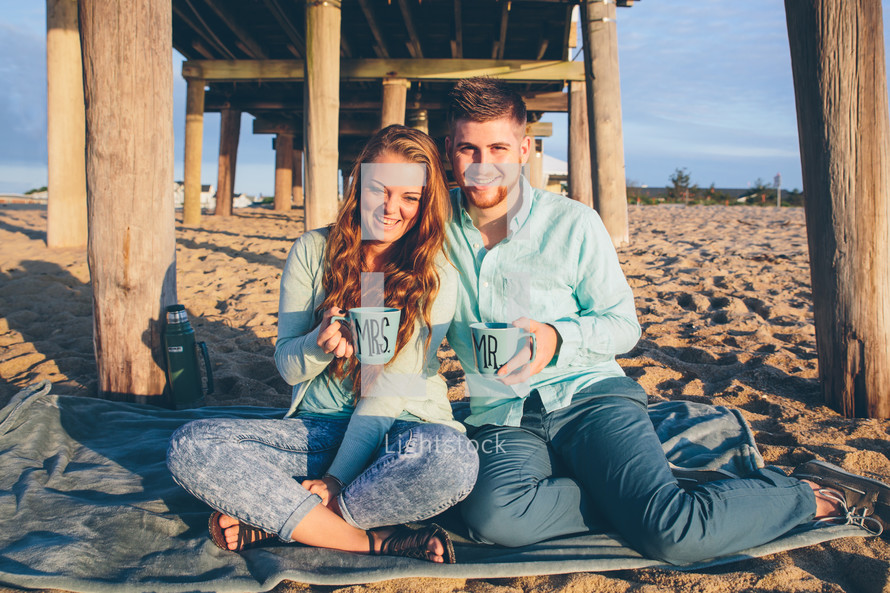 a couple on their honeymoon on a beach having a picnic 