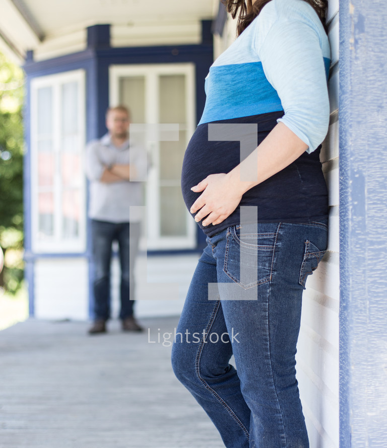 Expecting parents standing on the porch.