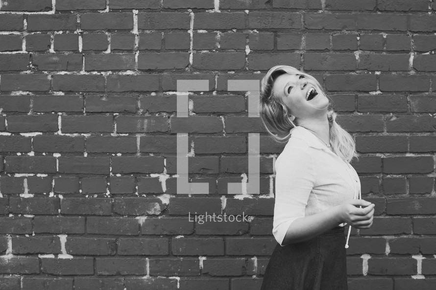 woman laughing and a brick wall 