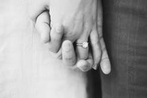 Engaged couple's intertwined hands.