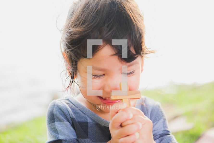 a toddler girl holding a wooden cross 