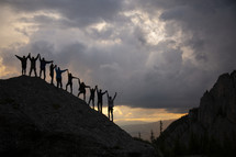 people holding hands standing on a mountainside 