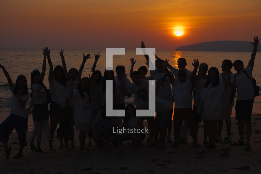 group of people on a beach at sunset 