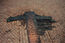 wood cross on brick road 