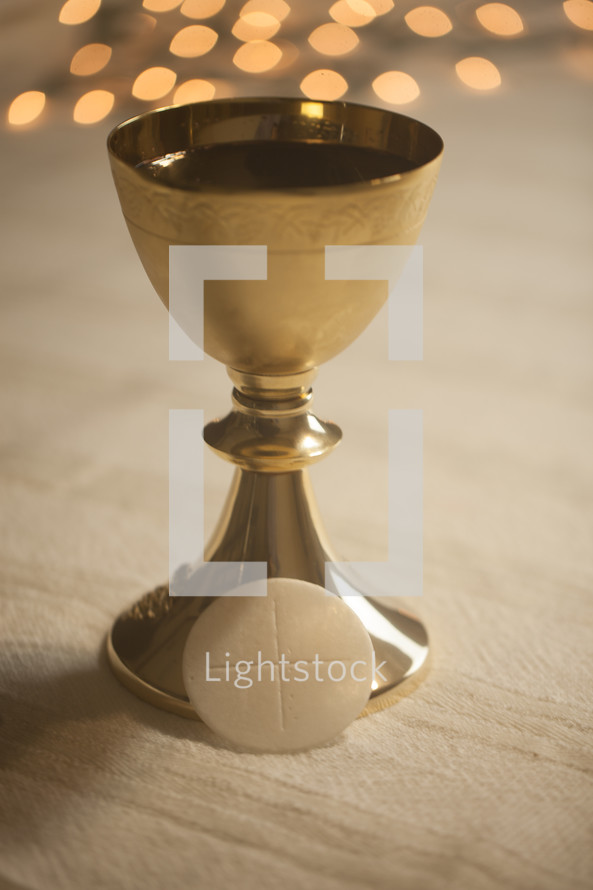 bokeh lights behind a chalice and host