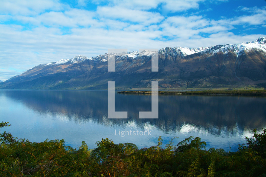 A range of snow capped mountains reflected in a clear lake