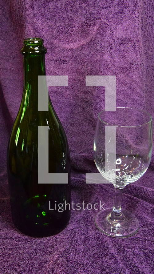 Wine bottle and glass with purple cloth background