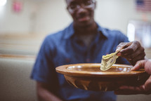 a man giving money to a tithe plate 