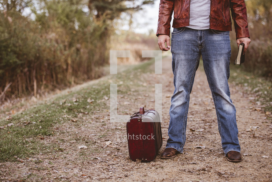 a man standing with a suitcase and Bible 