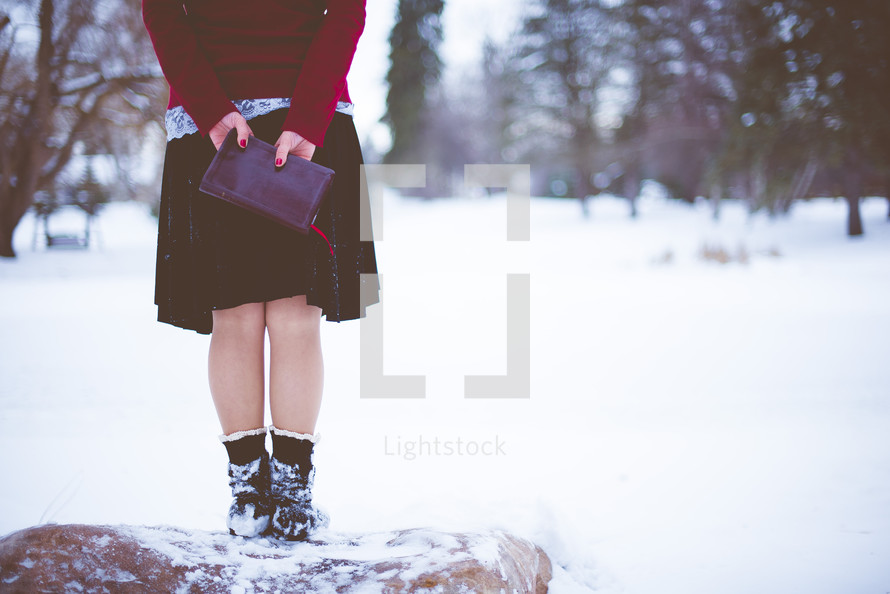 a woman holding a Bible outdoors in snow 
