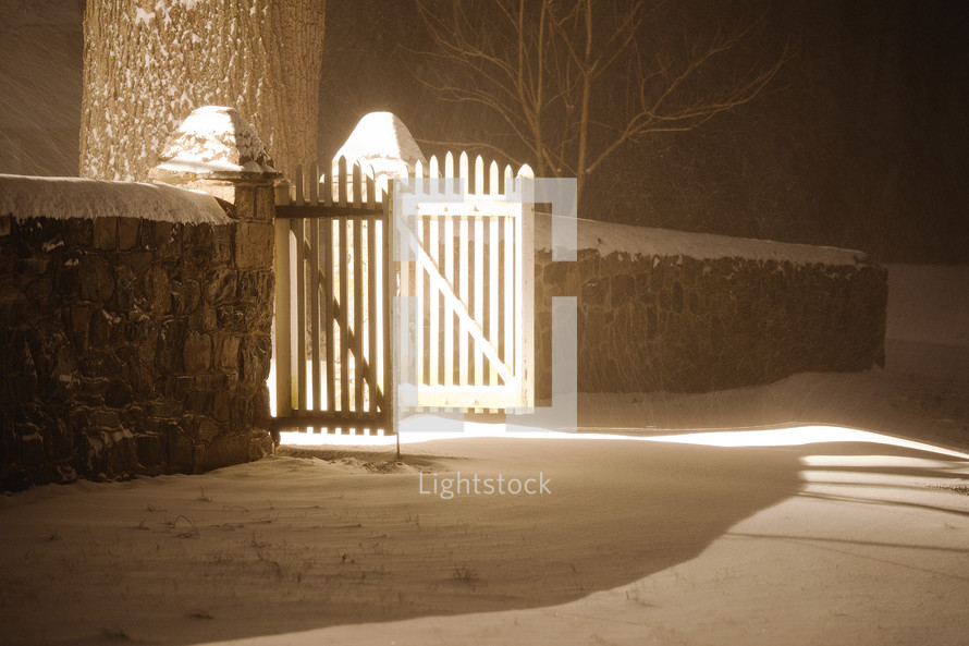open gate and snow on the ground at night 