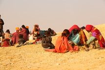 refugees resting in desert sand 