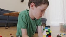 Young boy playing and constructing with toy bricks on the living room floor