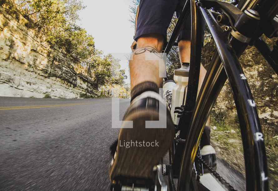Feet and legs of biker biking uphill.