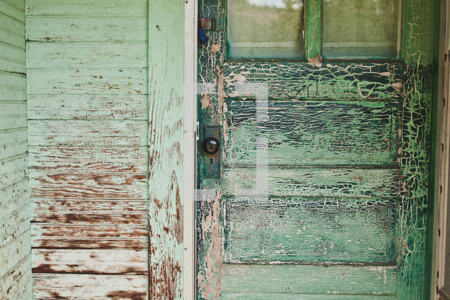 Porch of home with rustic door and weathered green paint.