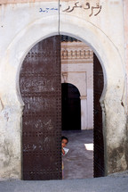 Child peeking through an ornate doorway
