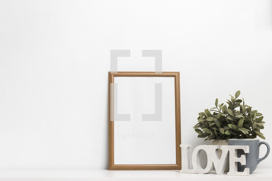 blank frame, love sign, and houseplant 
