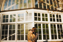 couple in an embrace standing outdoors in front of windows