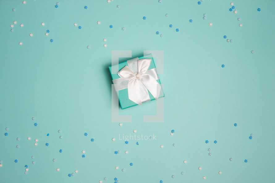 Small present with turquoise background with snowflake confetti