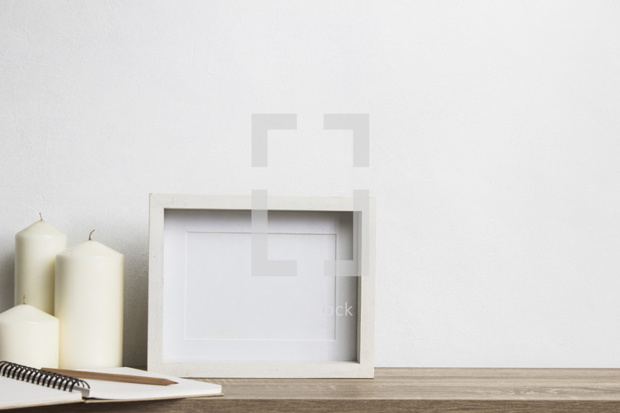 blank frame and three white candles 