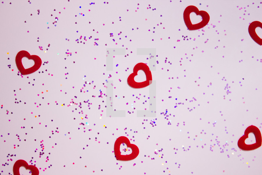 red hearts and glitter on a pink background 