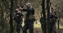 Squad of armed terrorists patrolling a forest area during combat