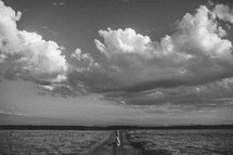 distant couple standing on a dirt road under a cloudy sky