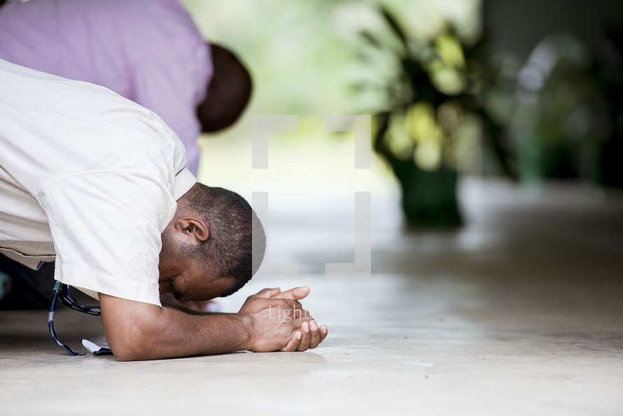 men kneeling in prayer during a worship service 