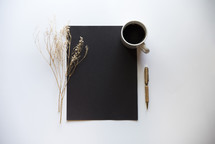 blank black paper, pen, coffee cup, and twig 