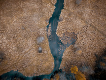 aerial view over a river and fall trees 