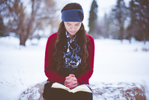 a woman reading a Bible in the snow 