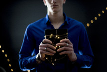 a man holding a Bible wrapped in fairy lights 