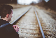 a man kneeling in prayer in the middle of train tracks 
