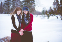 women praying outdoors in snow 