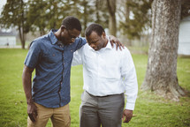 two African American men praying together 