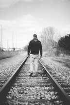 man walking in the middle of train tracks