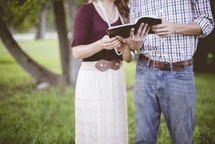 a couple reading a Bible together outdoors 