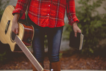 a woman holding a guitar and Bible 