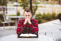 a man sitting at a table praying 