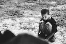 a squatting boy playing in dirt 