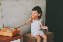 toddler girl talking on a vintage telephone 
