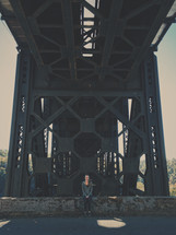 woman standing under a steel bridge 