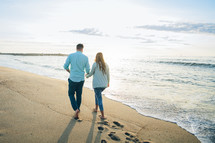 a couple walking on a beach 