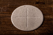 A communion wafer on a wooden surface.