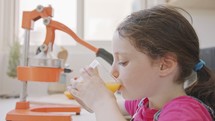 young cute girl drinking a glass of freshly squeezed orange juice