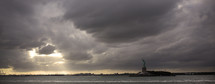 sunlight through the clouds over the Statue of Liberty
