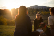 young women talking outdoors under golden sunlight 