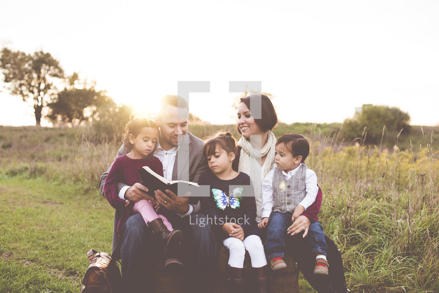 family reading a Bible together outdoors 