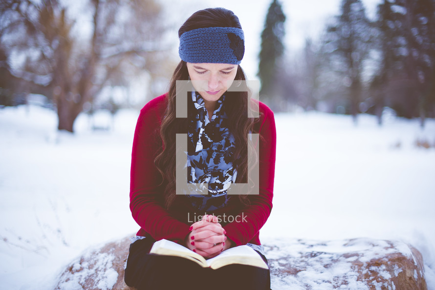 a woman reading a Bible in the snow 